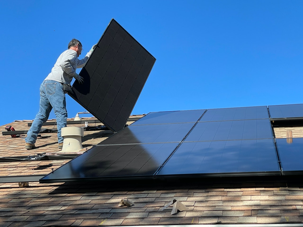 Technicien installant un panneau photovoltaïque sur toiture pour ACES, spécialiste en électricité et solutions solaires.